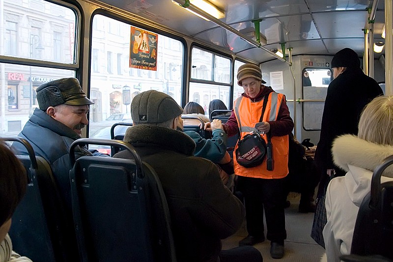 A conductor collects fares on a St. Petersburg bus